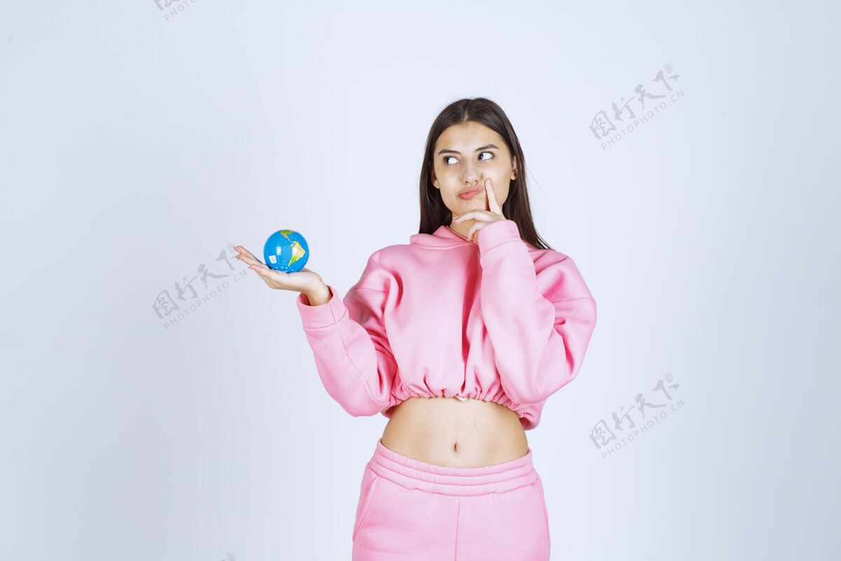 年轻人穿着粉色睡衣的女孩拿着一个迷你地球仪思考着年轻照片教育