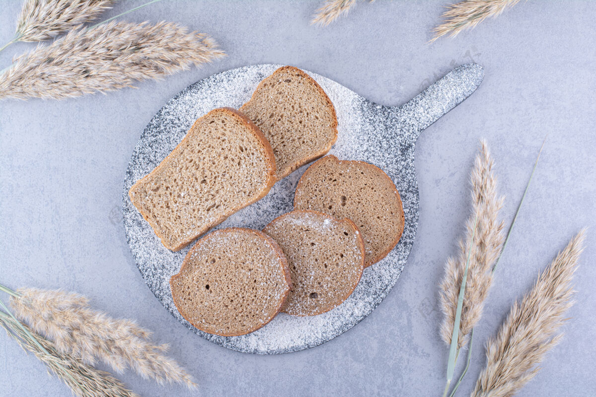 黑麦在大理石表面的羽毛草杆旁边 铺着面包片的面粉板羽毛草饮食面团