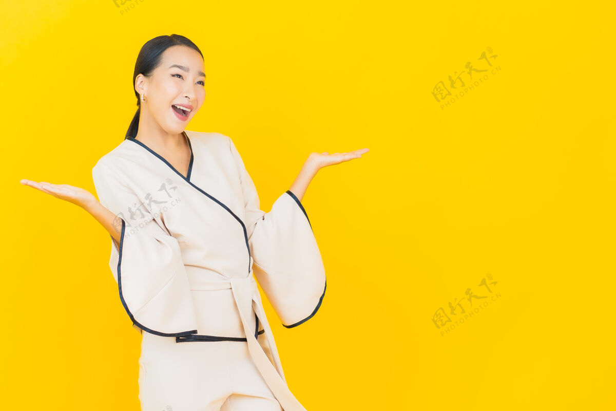 行政美丽的亚洲年轻商业女性在黄色墙上穿着白色西装微笑的画像美丽微笑脸