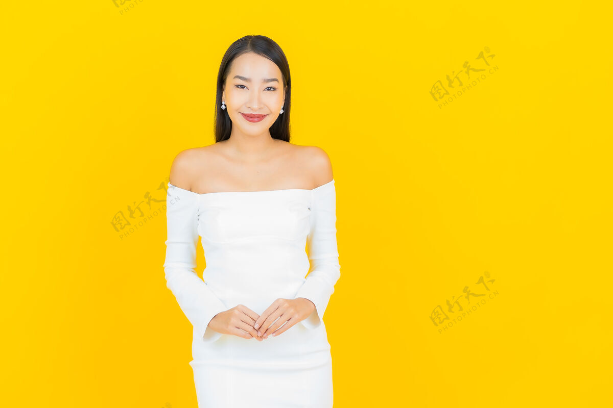 美丽美丽的亚洲年轻商业女性在黄色墙壁上穿着白色裙子微笑的画像女人成功亚洲人