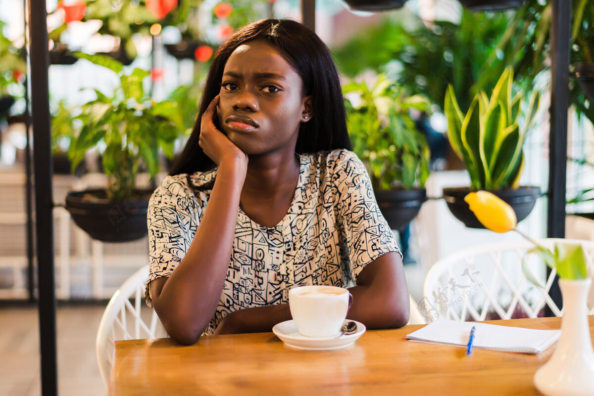 电子邮件漂亮的非洲裔美国女人坐在笔记本电脑旁的桌子旁 神情疲惫休闲使用咖啡馆
