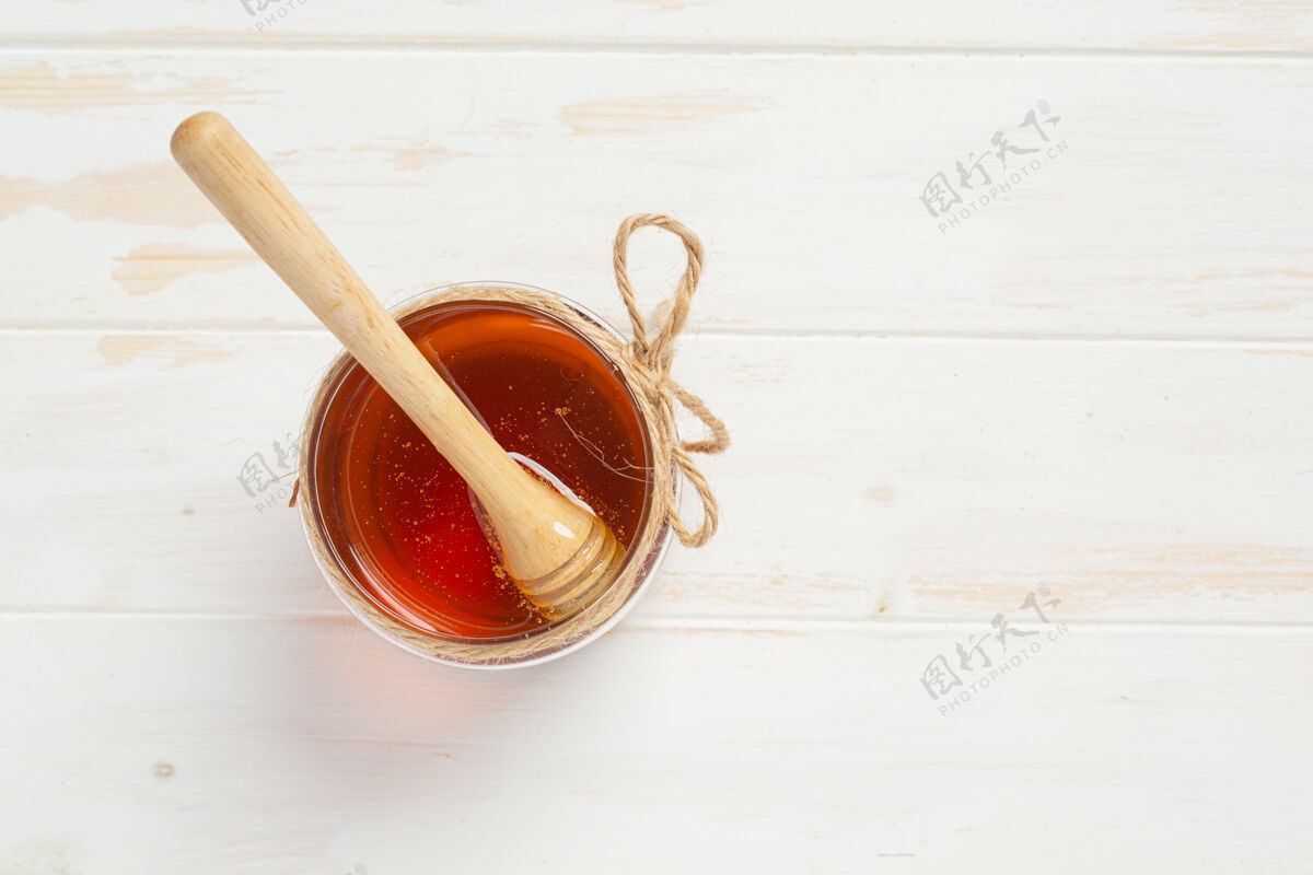 花蜜美味的蜂蜜在白色的木头表面食物木头棍子
