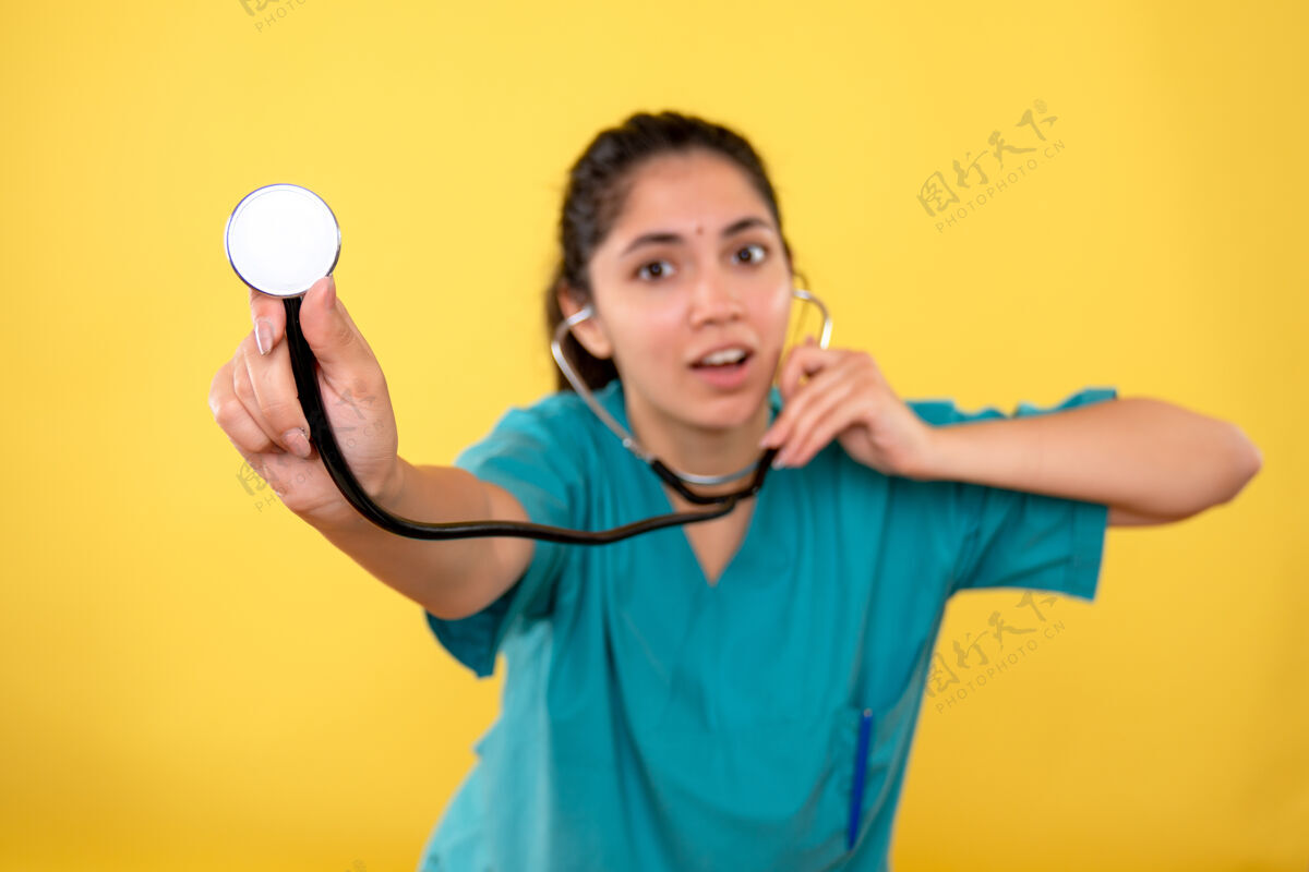 球员前视图穿着制服的年轻女医生在黄色背景上使用听诊器听诊器年轻人