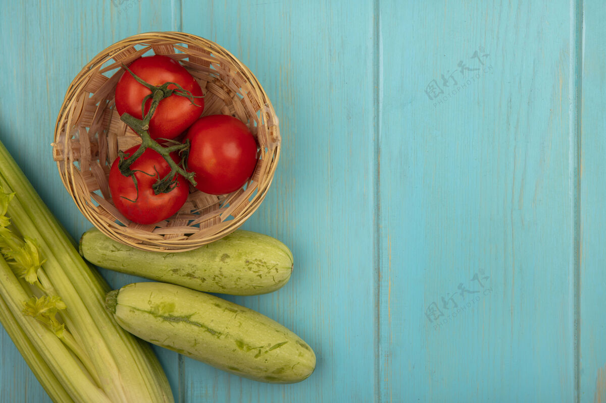 木材美味的西红柿与西葫芦和芹菜在一个蓝色的木制表面与复制空间隔离桶顶视图可口蔬菜桶装