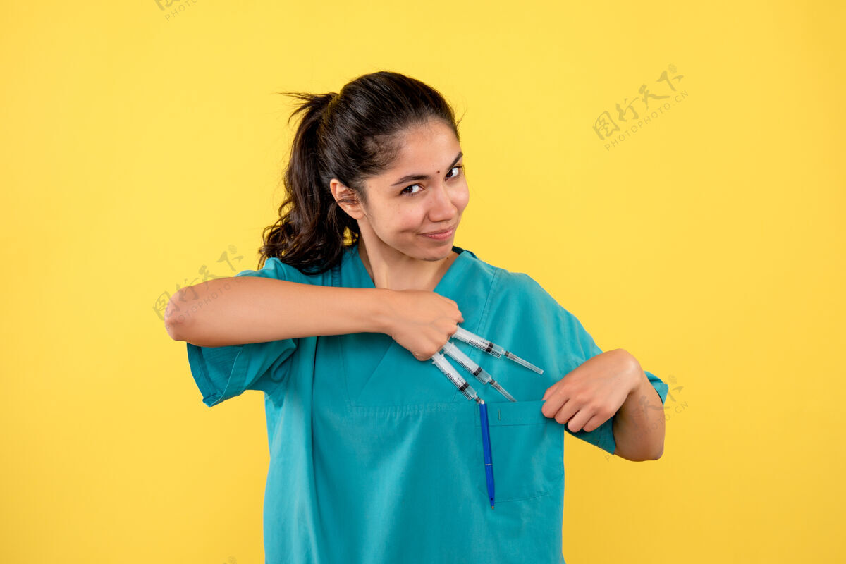 医生正面图微笑的女医生手持注射器站在黄色背景上微笑球员专业