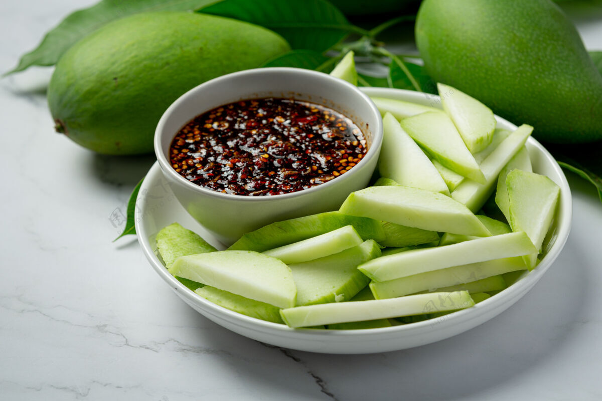 绿色新鲜的绿芒果和甜鱼露蘸在白色的表面美味小吃泰国