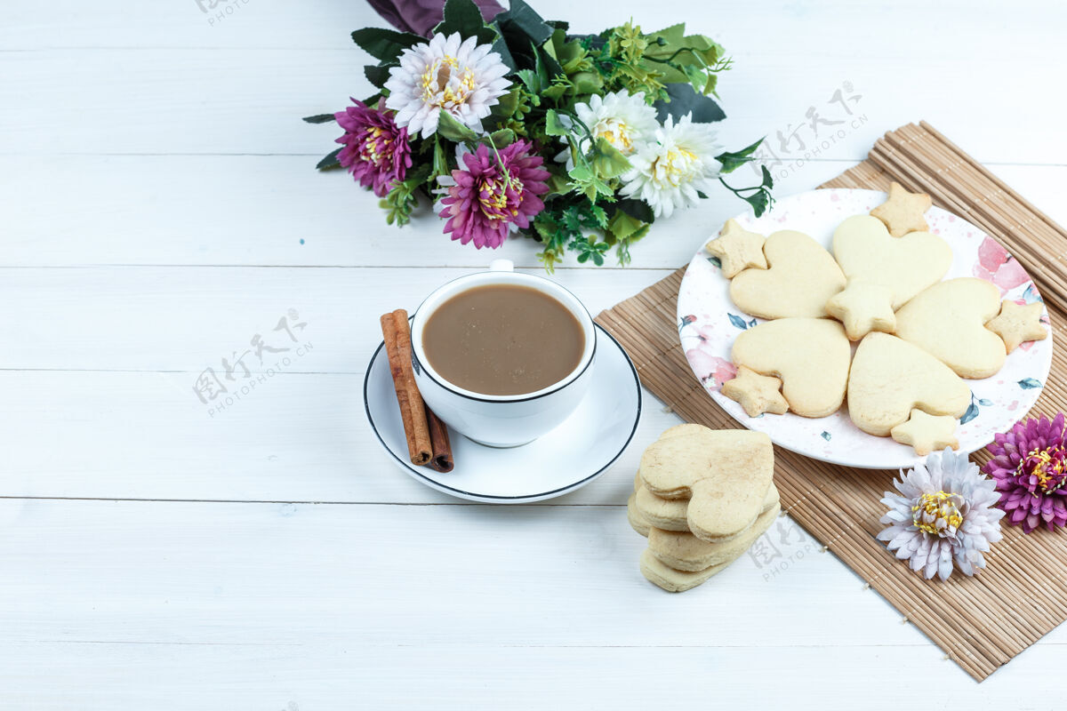 糕点高角度观看心形和星形饼干 放在垫子上的花和一杯咖啡水平脆饼干