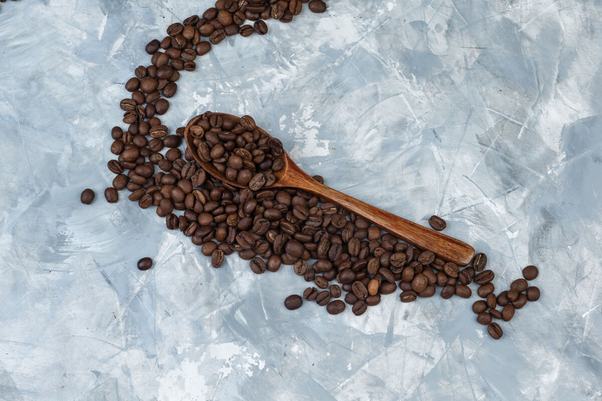 自然一些咖啡豆放在灰色灰泥背景的木勺里 平放着食物咖啡早晨