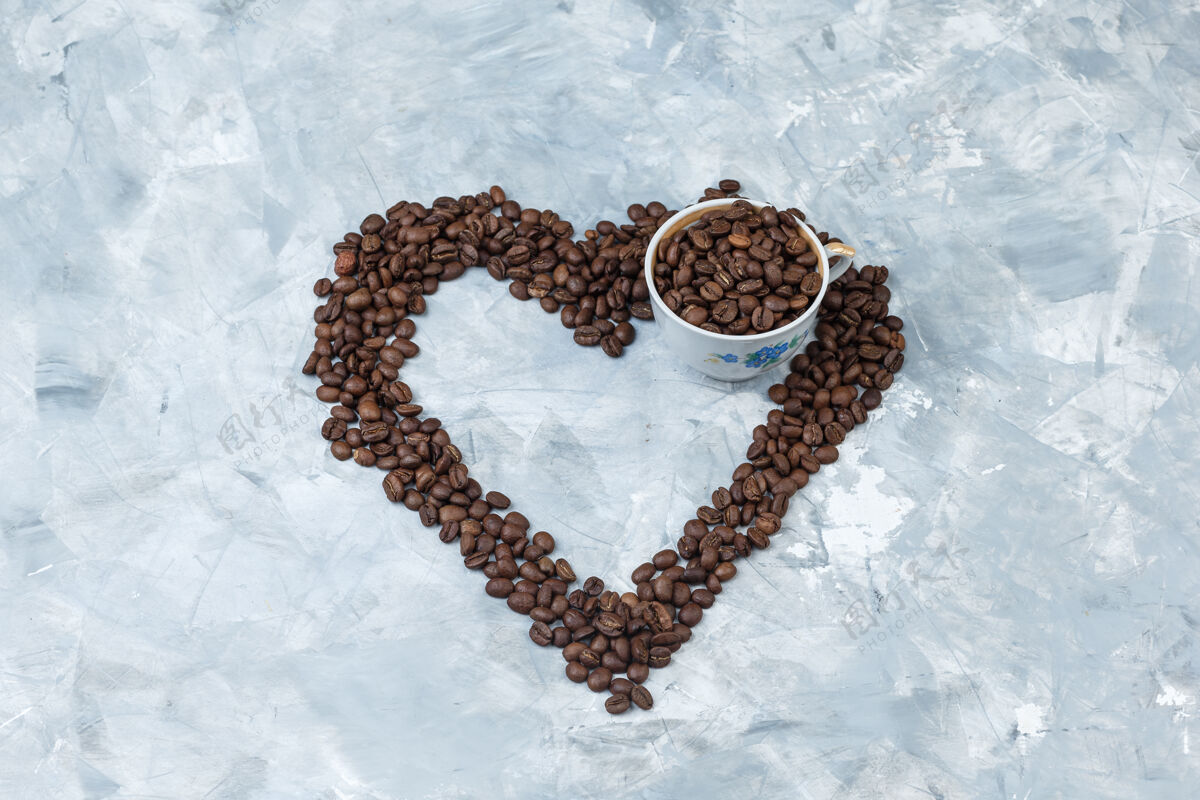 堆咖啡豆在一个灰色灰泥背景杯高角度的看法咖啡因阿拉比卡香味