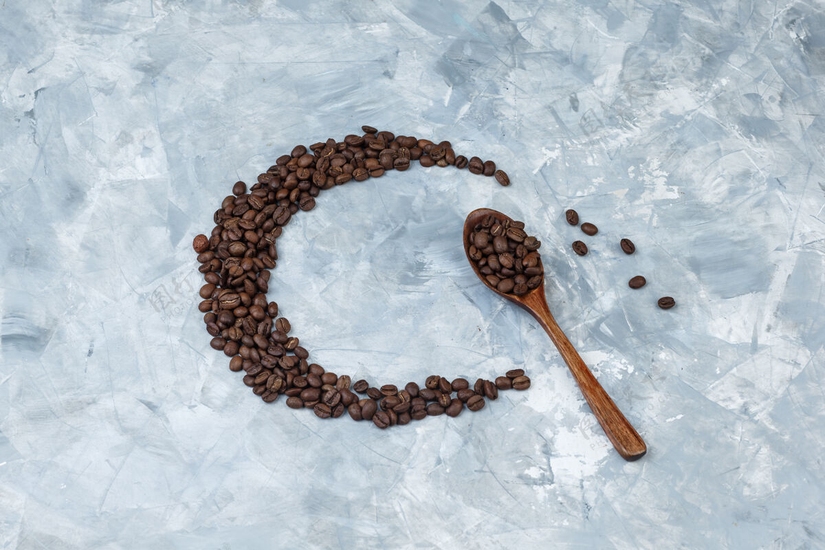 食物把咖啡豆平铺在灰色灰泥背景上的木勺里水平质地浓缩咖啡美食