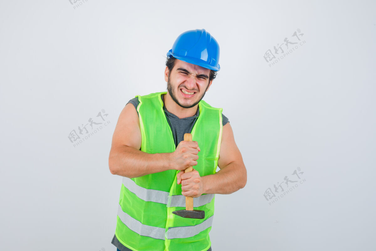 时尚年轻的建筑工人穿着工作服拿着锤子 看上去更强壮正视图正面建筑商相机