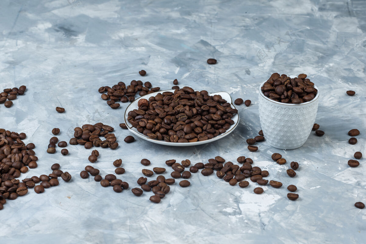 谷物咖啡豆在白色杯子和盘子上 灰色灰泥背景高角度视图石膏角香味