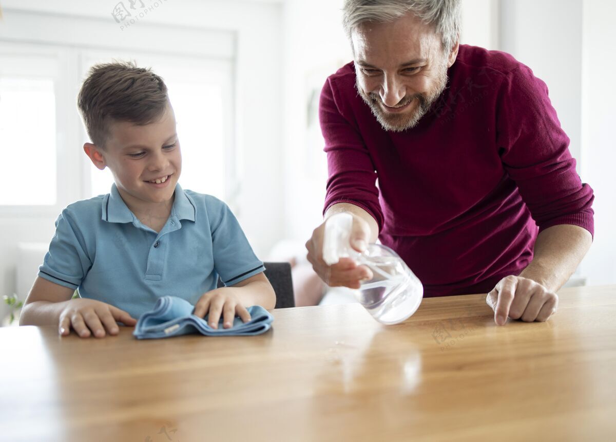 中景中枪的爸爸和孩子在擦桌子清洁父母室内