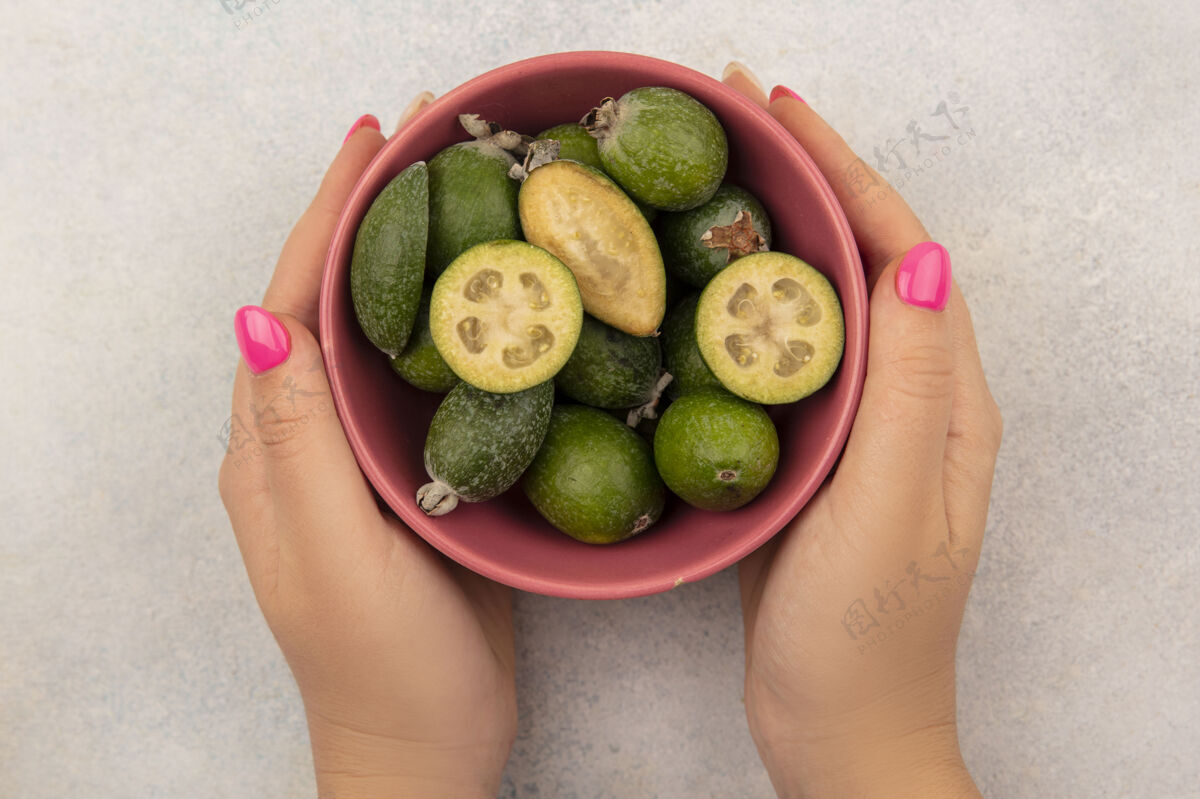手女性手拿着一碗健康的绿色熟透的飞珠在灰色表面的俯视图肥肉成熟女性