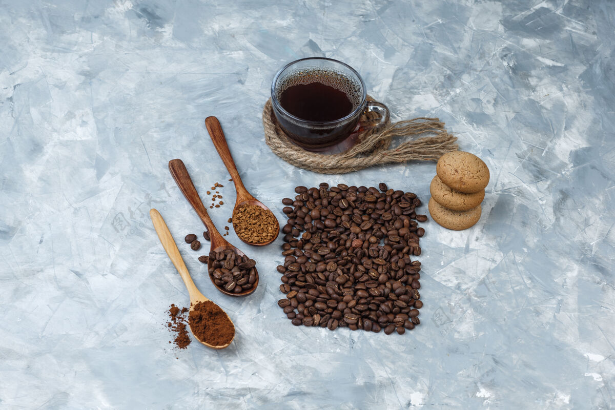 速溶一套咖啡豆 速溶咖啡 咖啡粉在木制勺子 绳子 饼干和咖啡豆 咖啡杯浅蓝色大理石背景平放绳子意式咖啡木头