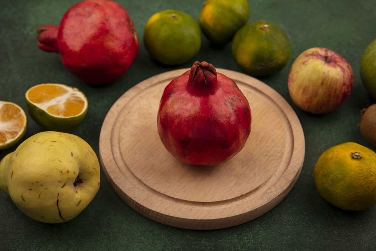 苹果站在石榴架上 绿色墙上挂着梨子 橘子和苹果食品前面橘子
