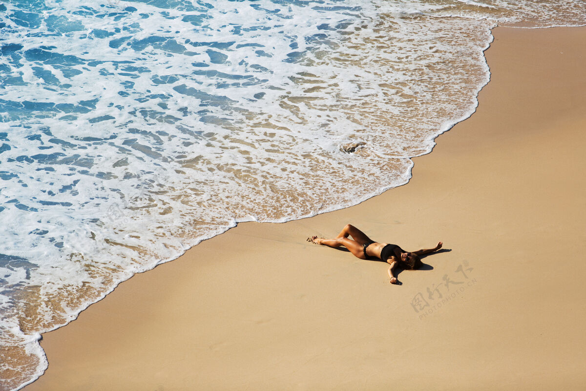 沙滩美丽的女孩在荒野的海滩上放松从顶部看风景很美海洋自由风景