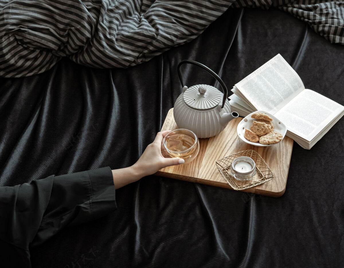 茶杯舒适的构图 一杯茶在女性手中 饼干和一本书在床上饼干马克杯美味