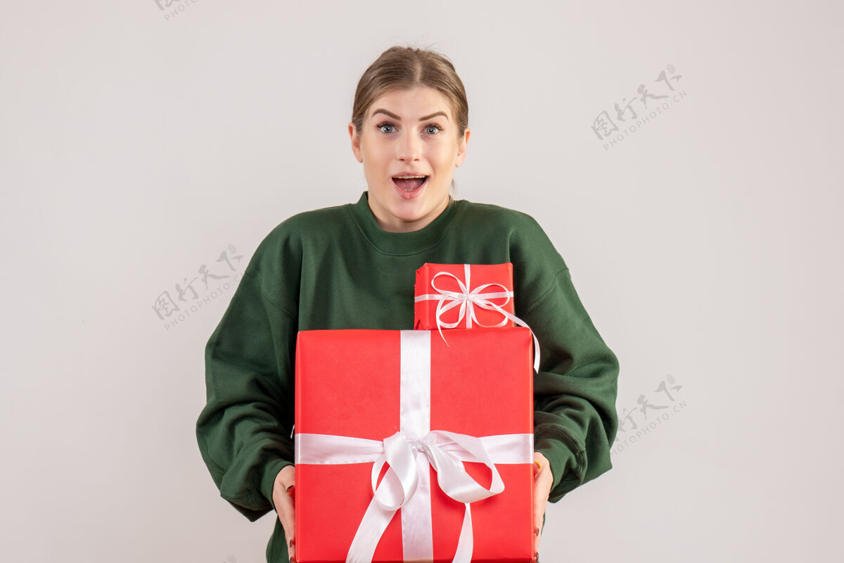 年轻女性年轻的女性手持圣诞礼物在白色衣服携带人