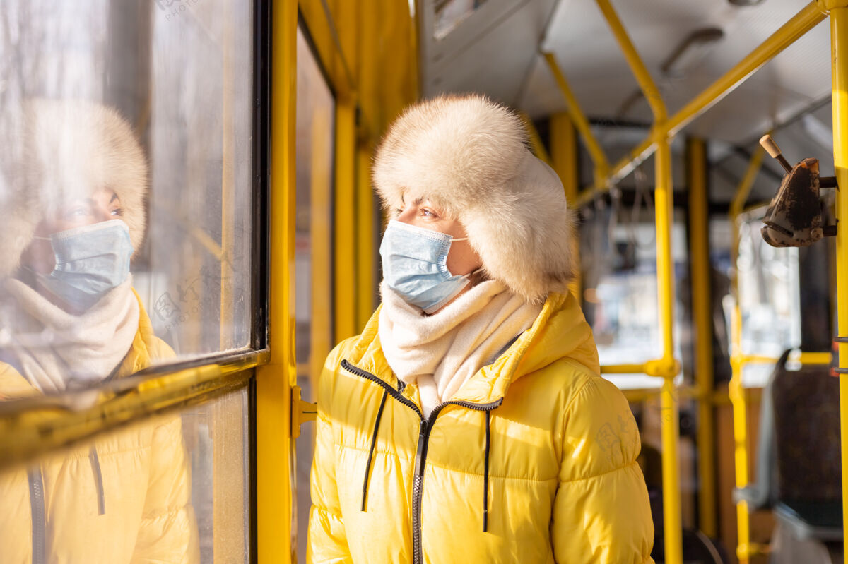 时髦一个穿着暖和衣服的年轻女子在一个冬天的城市公共汽车上的明亮的阳光肖像车站穿着围巾