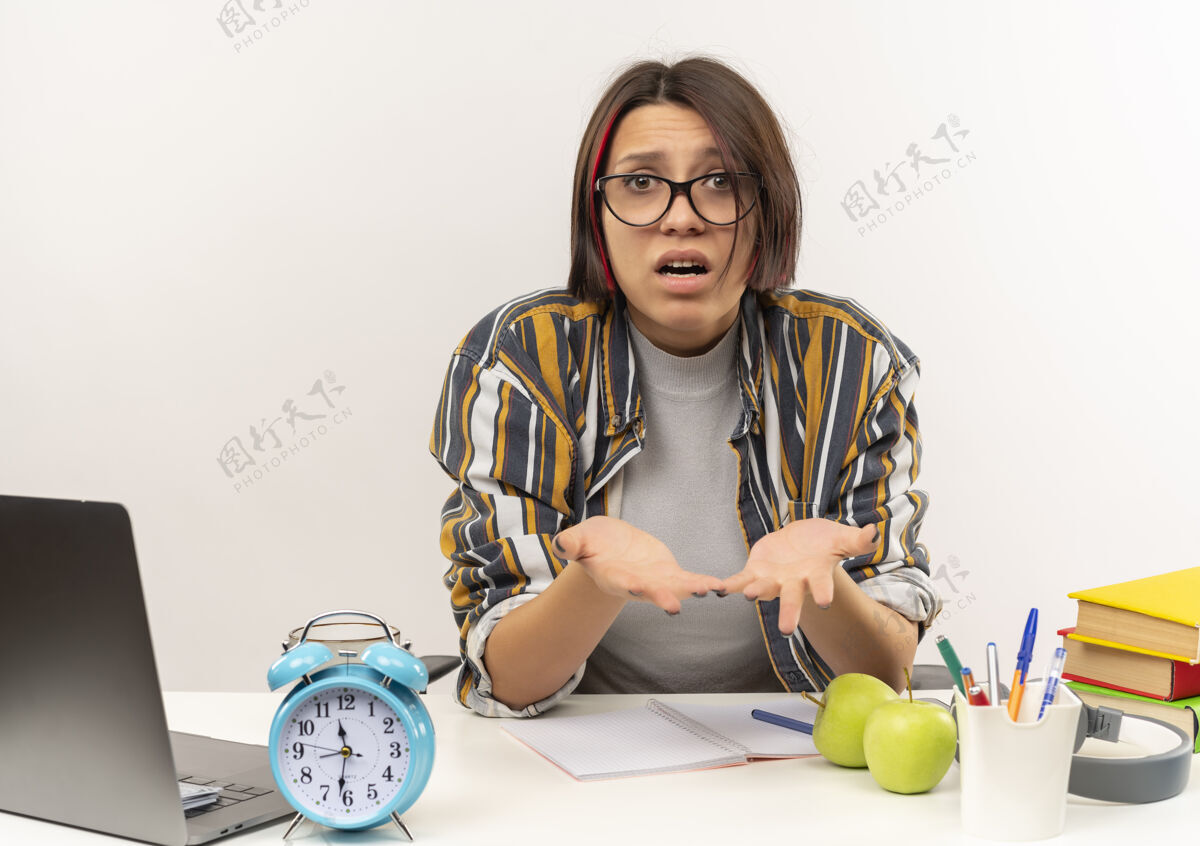 年轻迷茫的年轻女学生戴着眼镜坐在书桌旁 两手空空的 孤零零的站在白纸上眼镜困惑学生