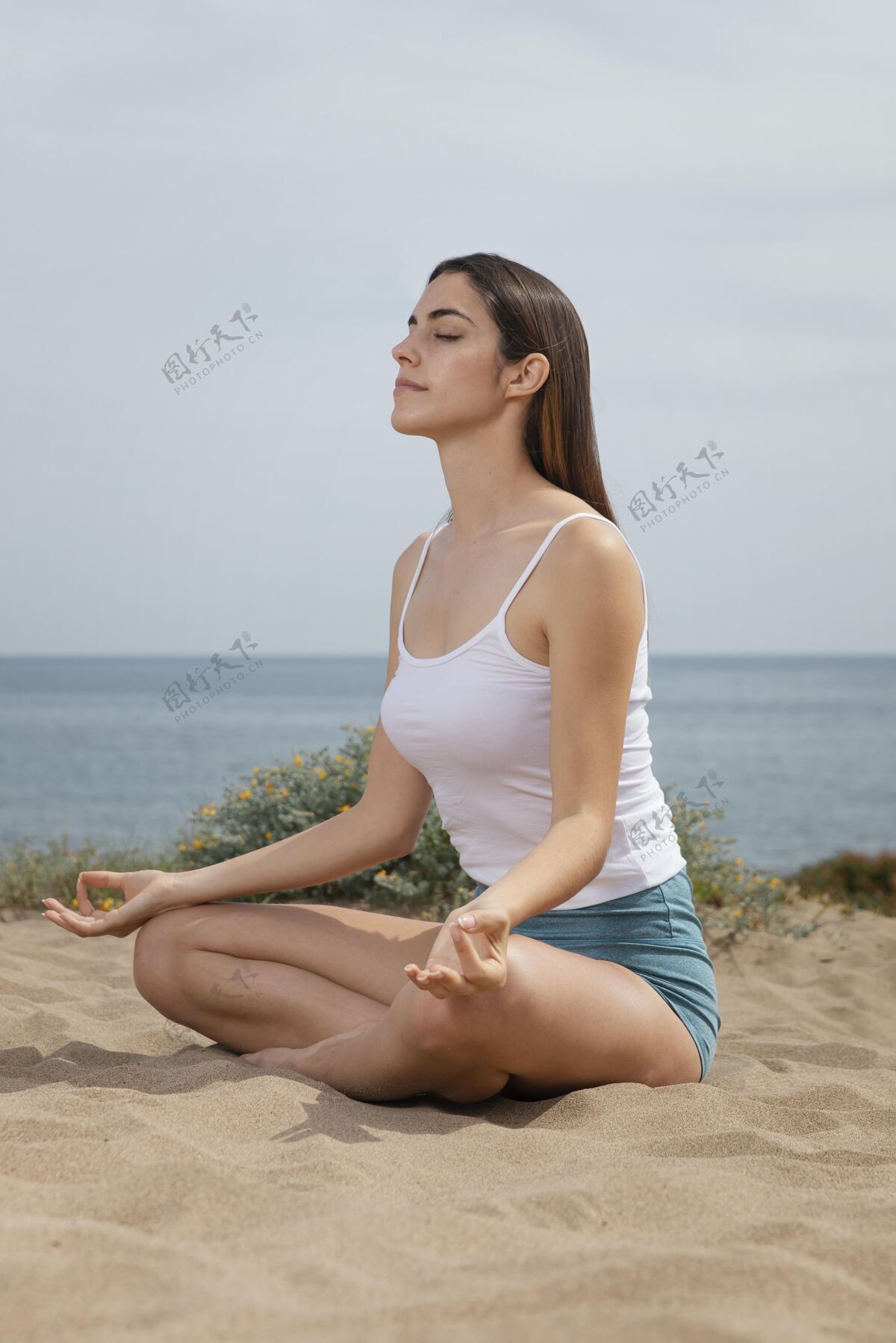 瑜伽在沙滩上打坐的年轻女子身体平衡姿势放松