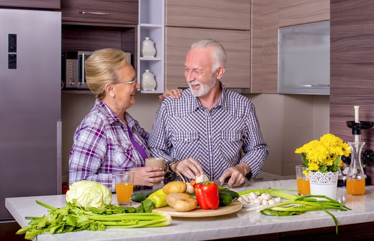 在一起美丽的老夫妇在厨房里一起做饭微笑老人欢呼