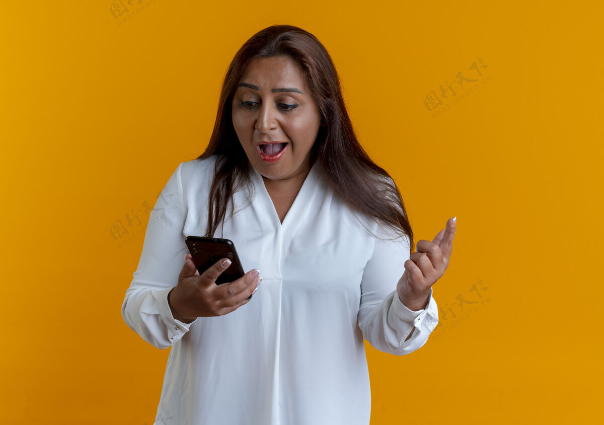 中年惊讶的是 随意的白人中年妇女抱着电话 看着隔离在黄色墙上的电话抱着惊喜女人