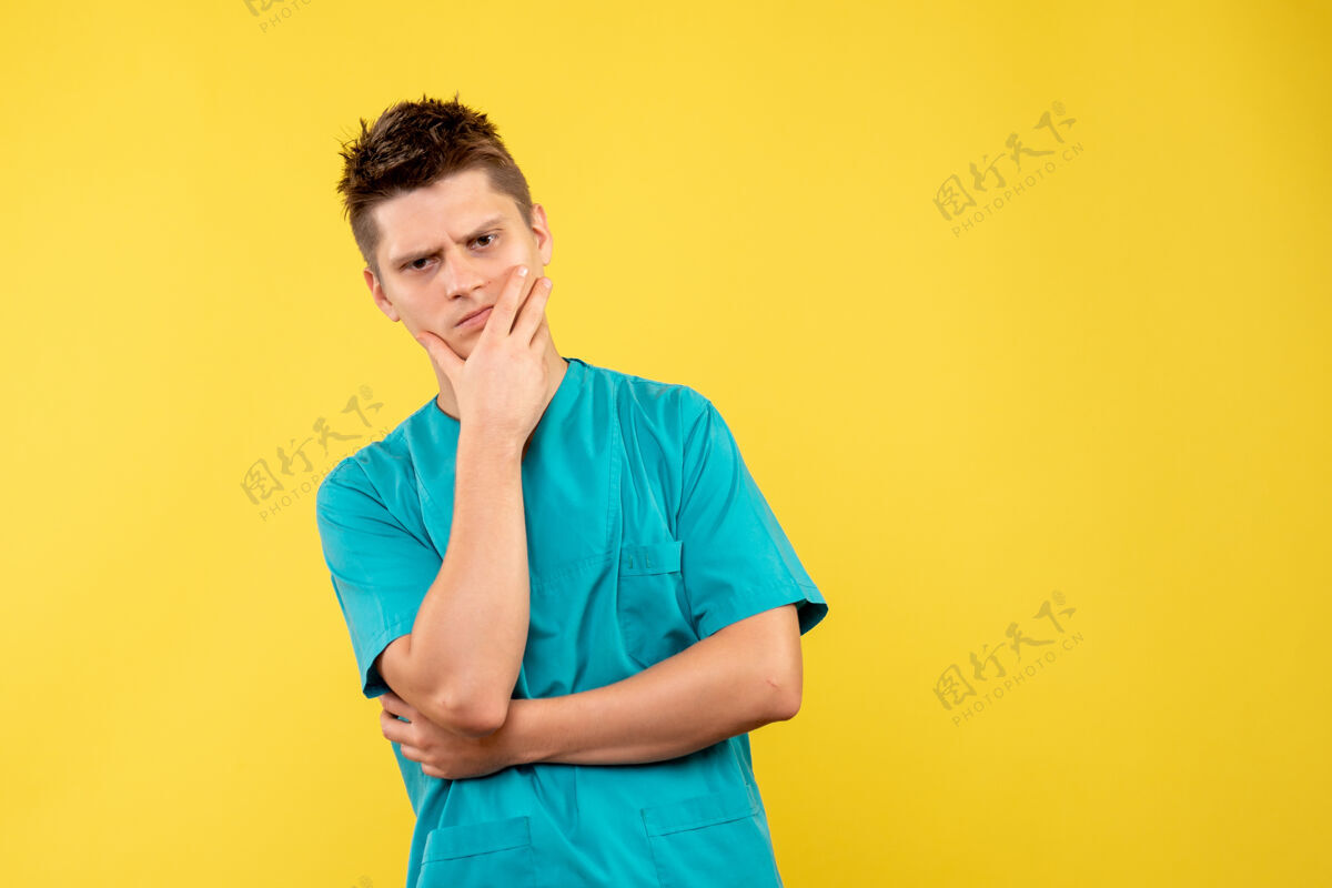 年轻男性医生正面图黄色背景上穿着医疗服的年轻男医生医学人健康