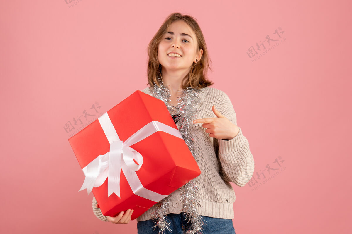 粉色手持圣诞礼物的年轻女性看法女士购物者