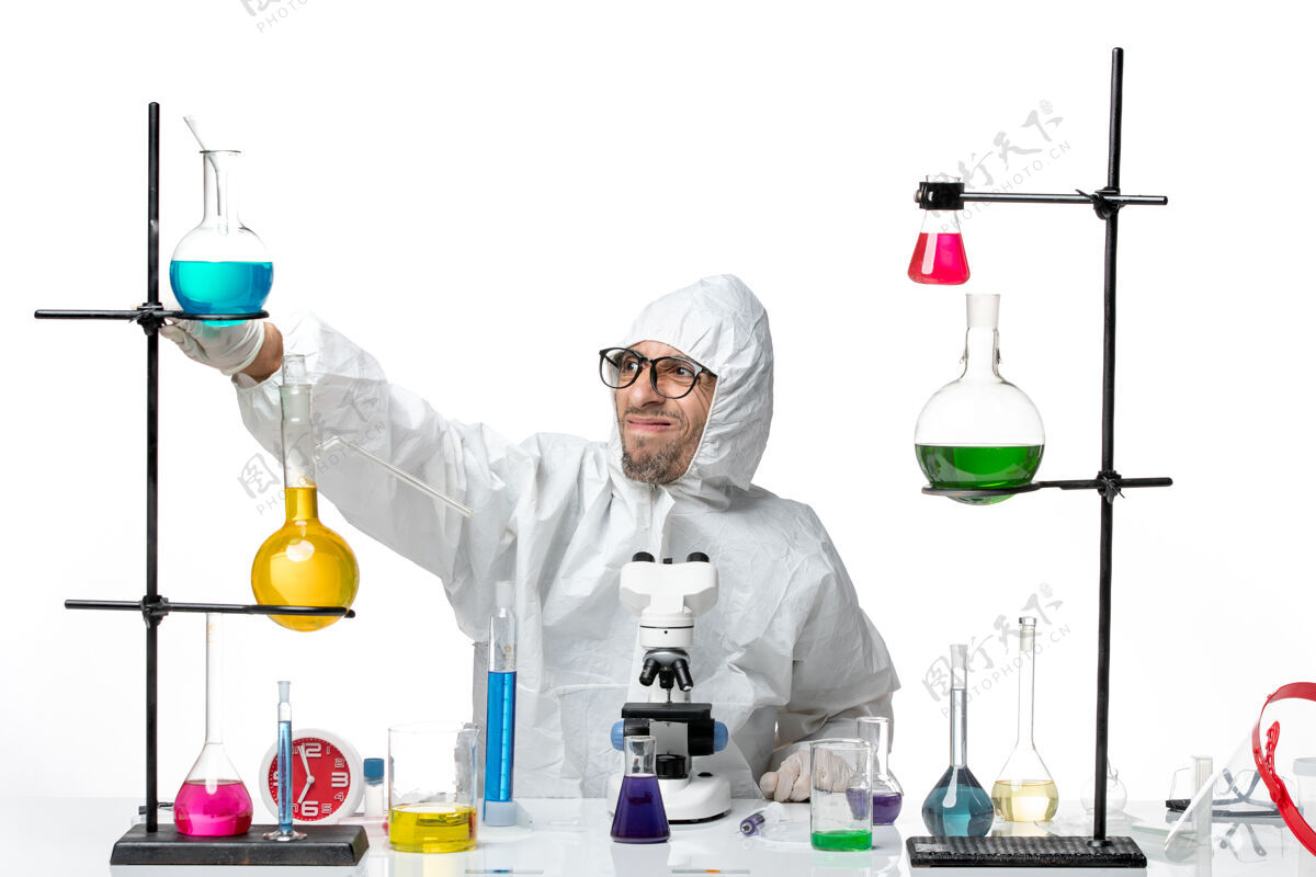 保护正面图穿着特殊防护服的男科学家围坐在桌子旁 拿着解决方案坐着化学实验室