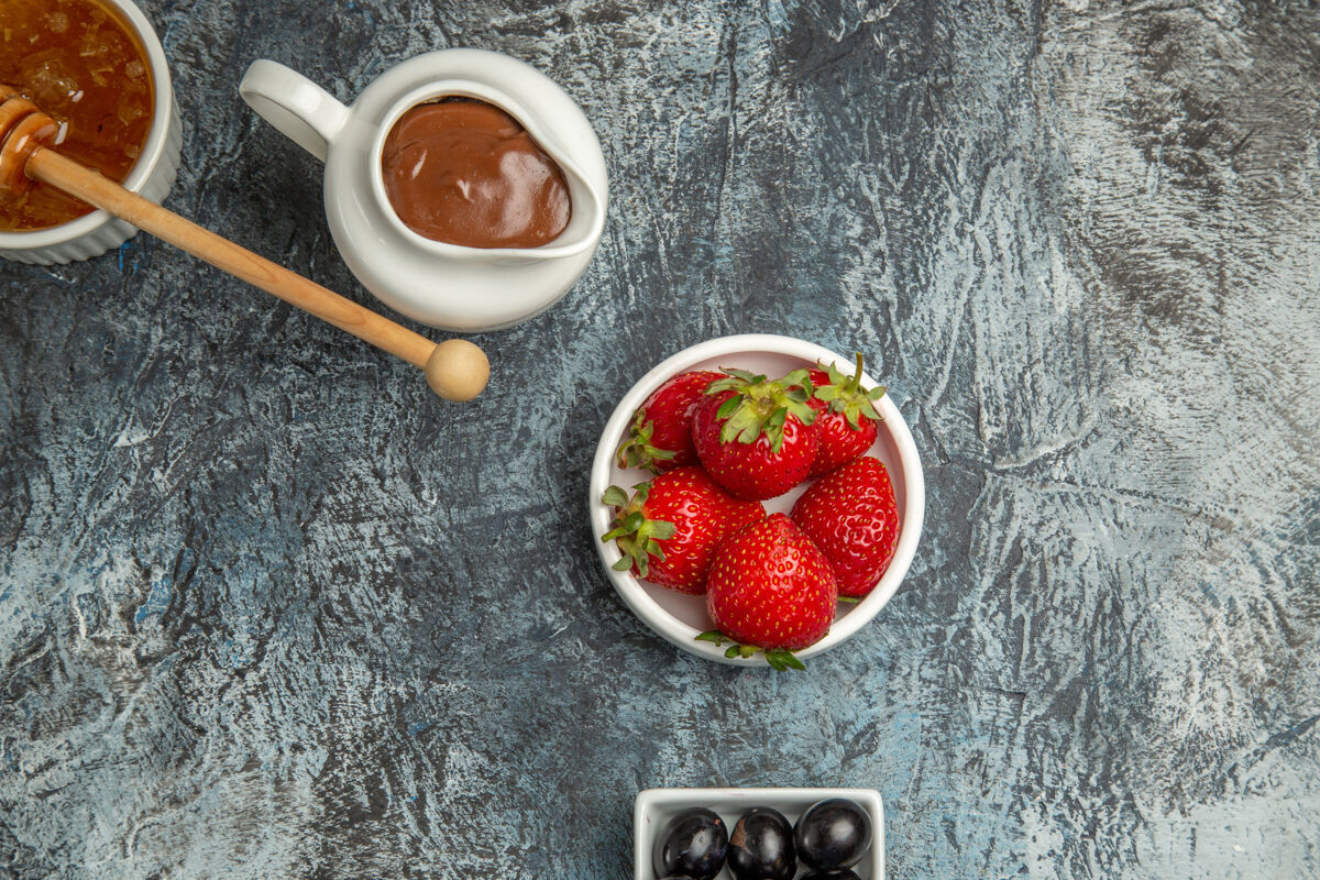 顶部顶视图新鲜草莓与橄榄和蜂蜜在黑暗的表面甜美的水果浆果食物膳食甜点