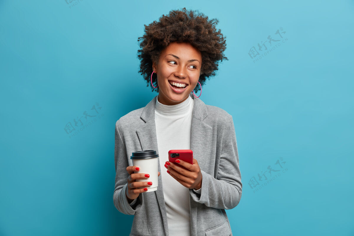 乐观成功的美国黑人企业家 穿着正装 手持手机 在网上点午餐 喝外卖咖啡 查看信息 约会 面带灿烂笑容灰色移动牙齿