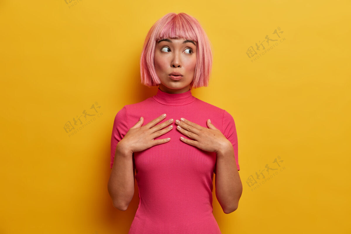 时尚人类的情感 反应和态度观念美丽的粉红头发的年轻女子双手放在胸前 一边带着好奇的表情看着她情感年轻和平