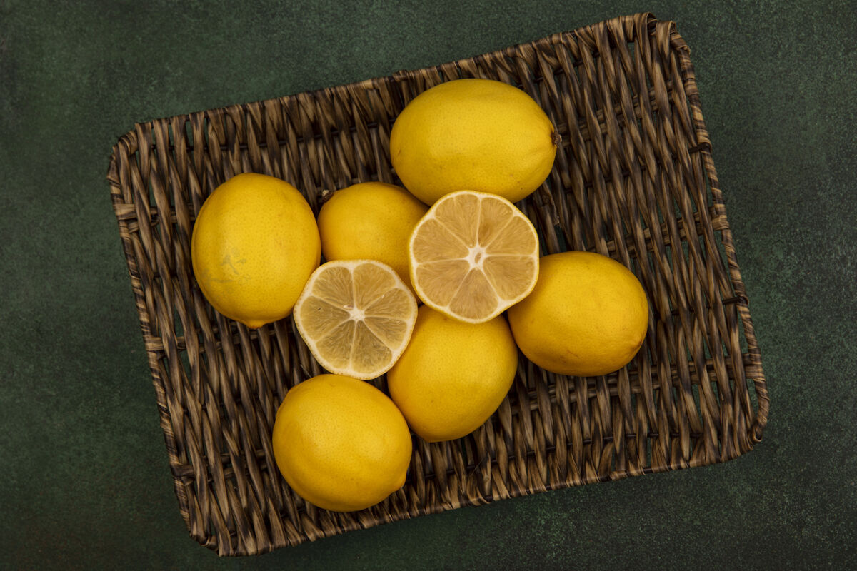 顶部绿色墙上柳条托盘上多汁的黄色柠檬的俯视图配料厨房多汁