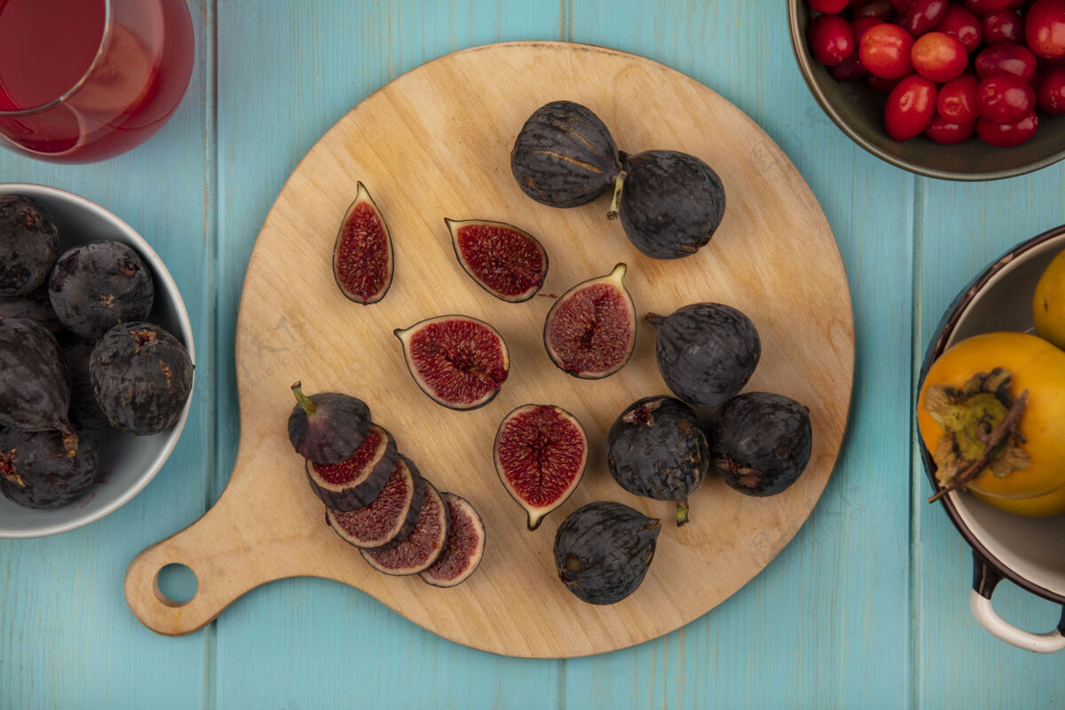 厨房新鲜的黑色任务无花果在一个木制厨房板与柿子水果在一个蓝色的木制墙上碗顶视图食品新鲜成熟