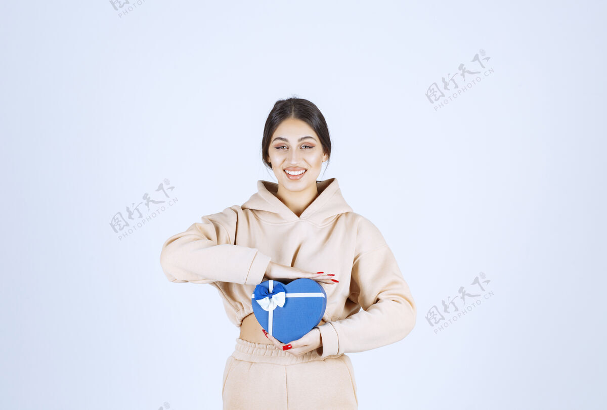 姿势年轻女子拿着一个蓝色心形礼盒 看起来很开心工人周年纪念成人