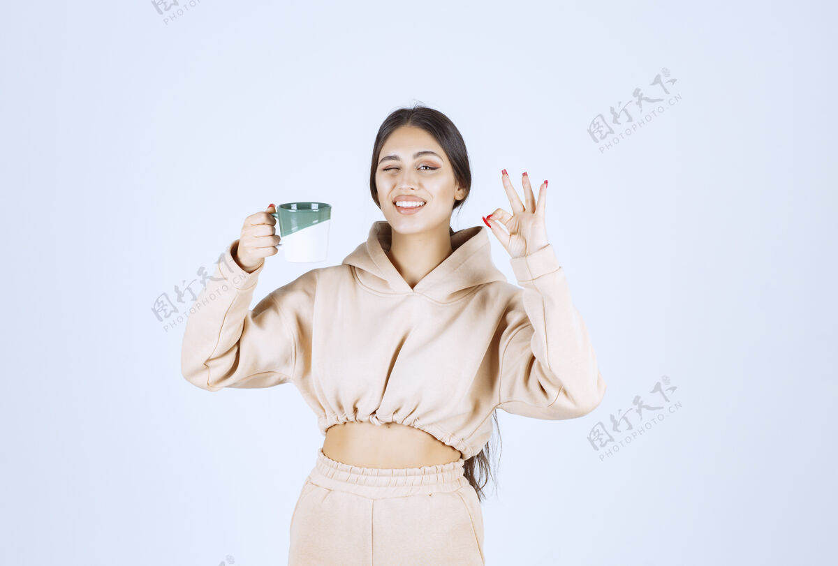 姿势一个年轻的女人拿着一个绿色的杯子 表示她的满足女性休闲年轻