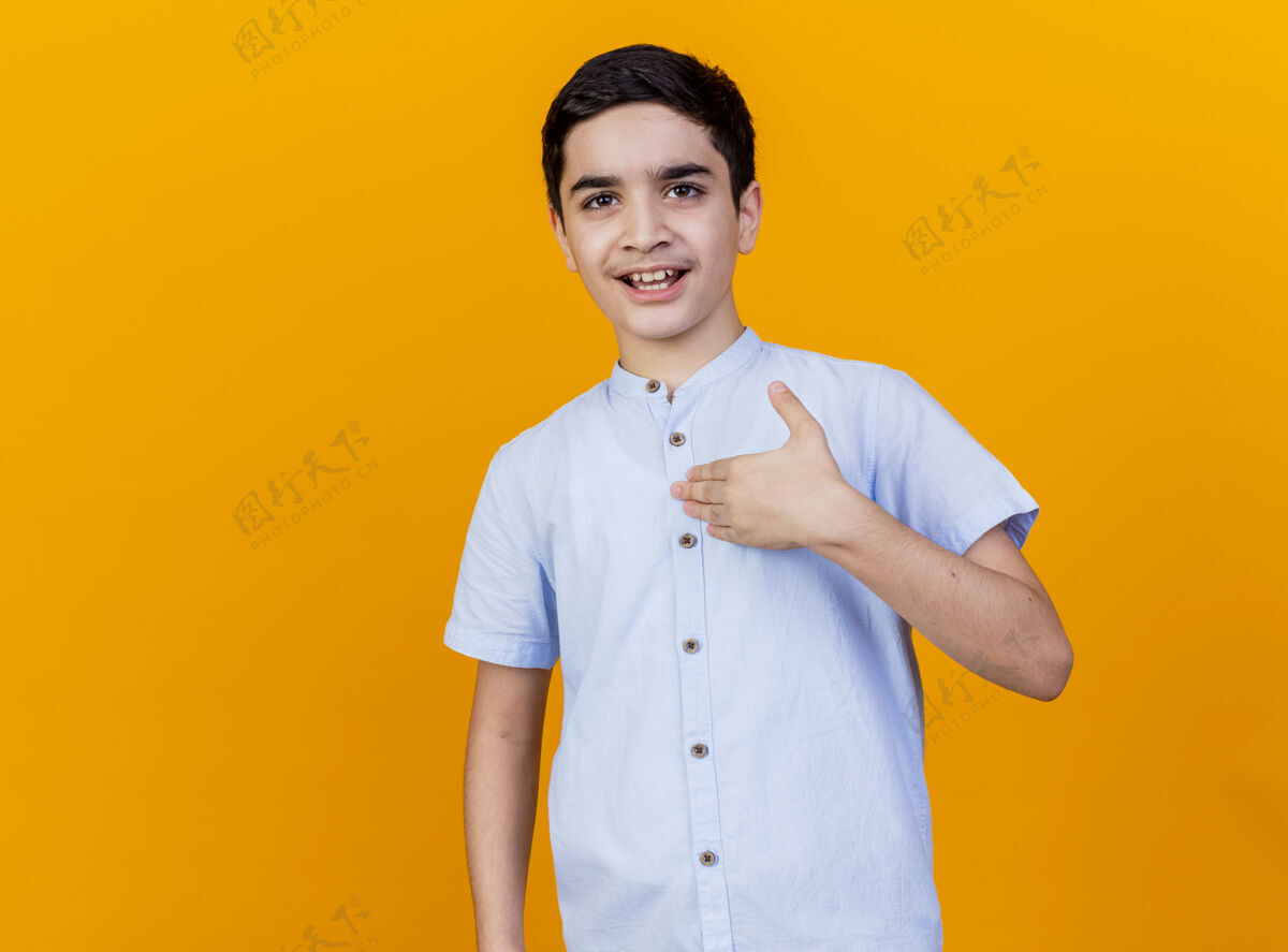 男孩令人印象深刻的年轻白人男孩看着相机触摸胸部孤立的橙色背景与复制空间复制印象触摸