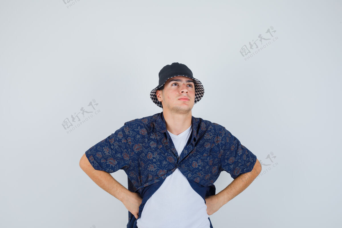 腰小男孩穿着白色t恤 花衬衫 戴着帽子 双手放在腰上 神情沉思 俯瞰前方青少年童年时尚
