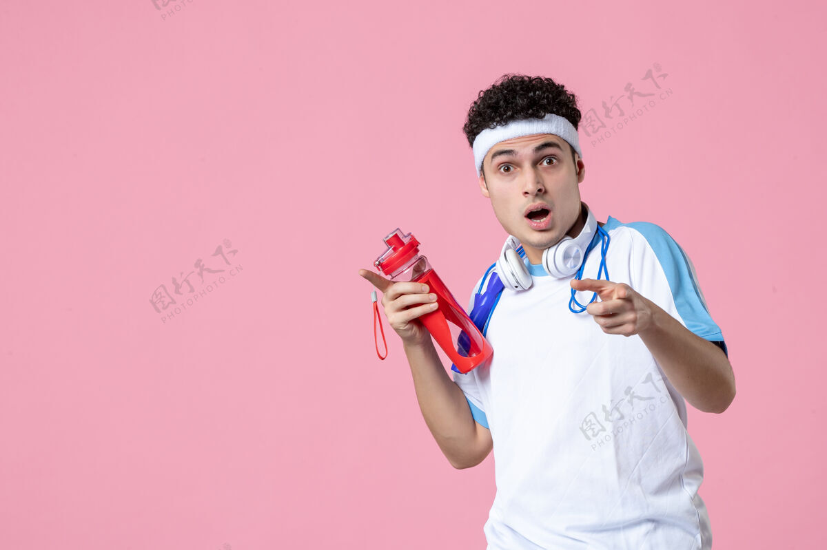 绳子正面图穿着运动服的年轻男性 粉色墙上有跳绳和水查看健身房运动