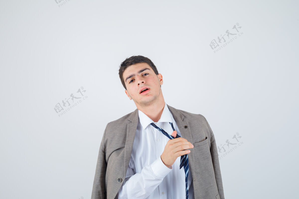 孤独在衬衫 夹克 条纹领带摆姿势时 男孩松开领带的肖像 看起来很疲惫的前视图无聊肖像年轻