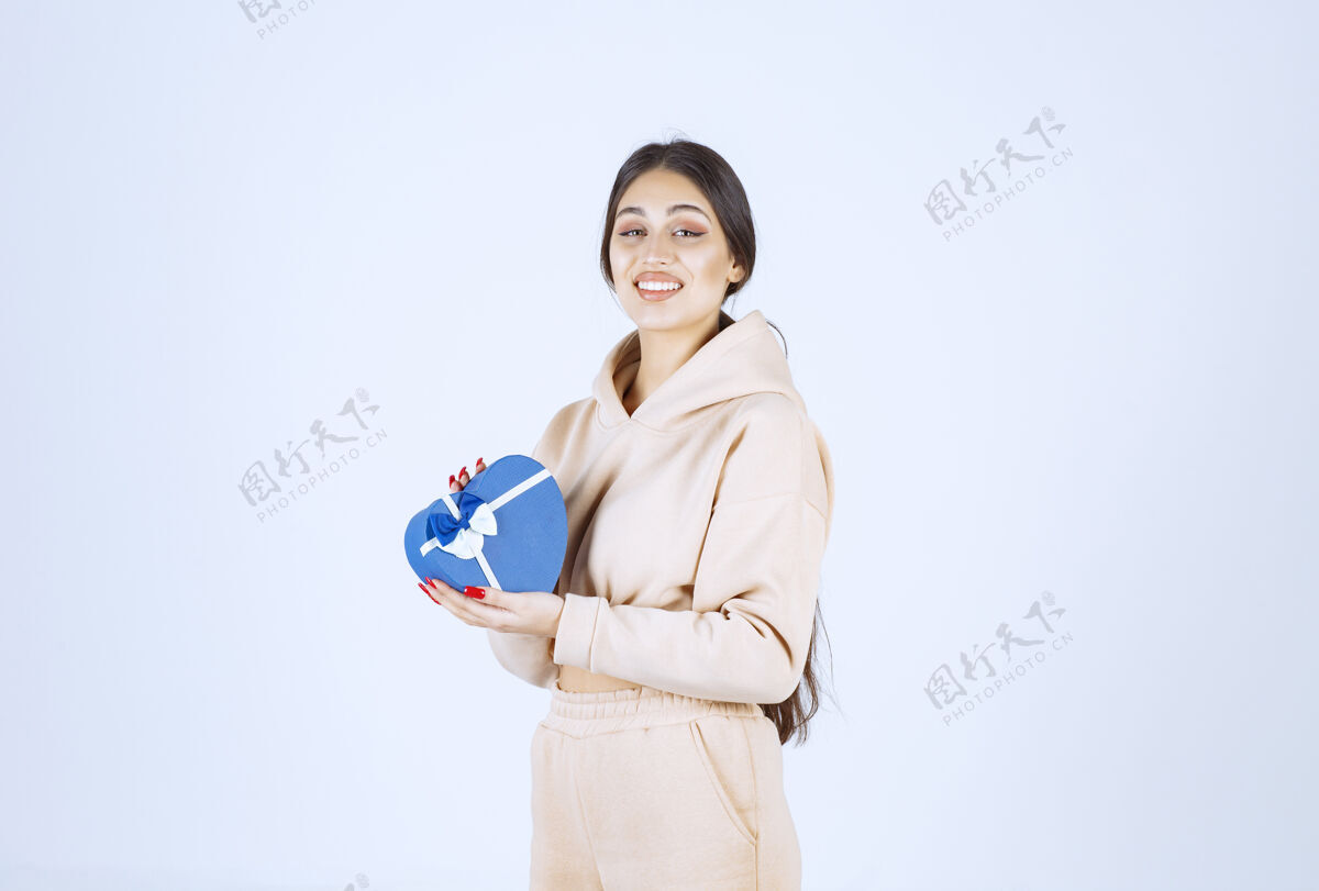 姿势年轻女子拿着一个蓝色心形礼盒 看起来很开心聪明周年纪念人