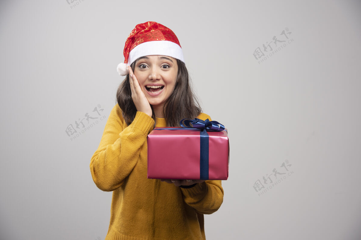 冬天微笑的戴着圣诞帽的女人手里拿着礼品盒圣诞节欢呼人