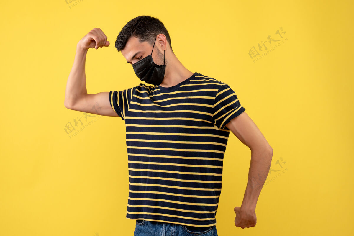 肌肉正面图身穿黑白条纹t恤的年轻人在黄色背景上展示肌肉正面肖像秀