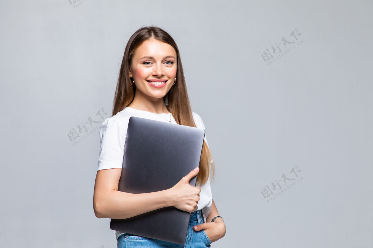 学习快乐的年轻女子拿着笔记本电脑摆姿势年轻个人电脑人