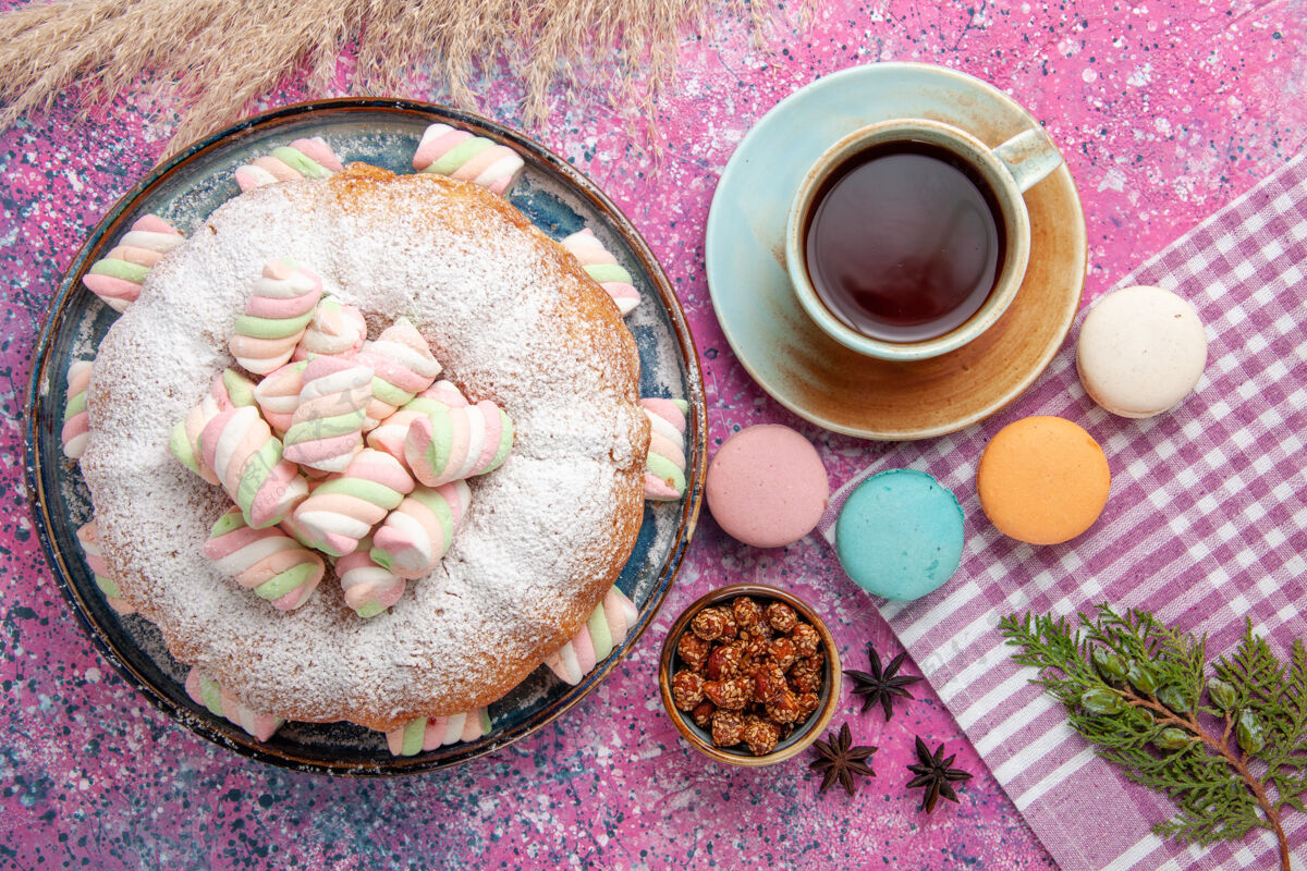 棉花糖糖粉蛋糕的俯视图 粉红色的表面上有棉花糖和一杯茶顶视图可口粉末