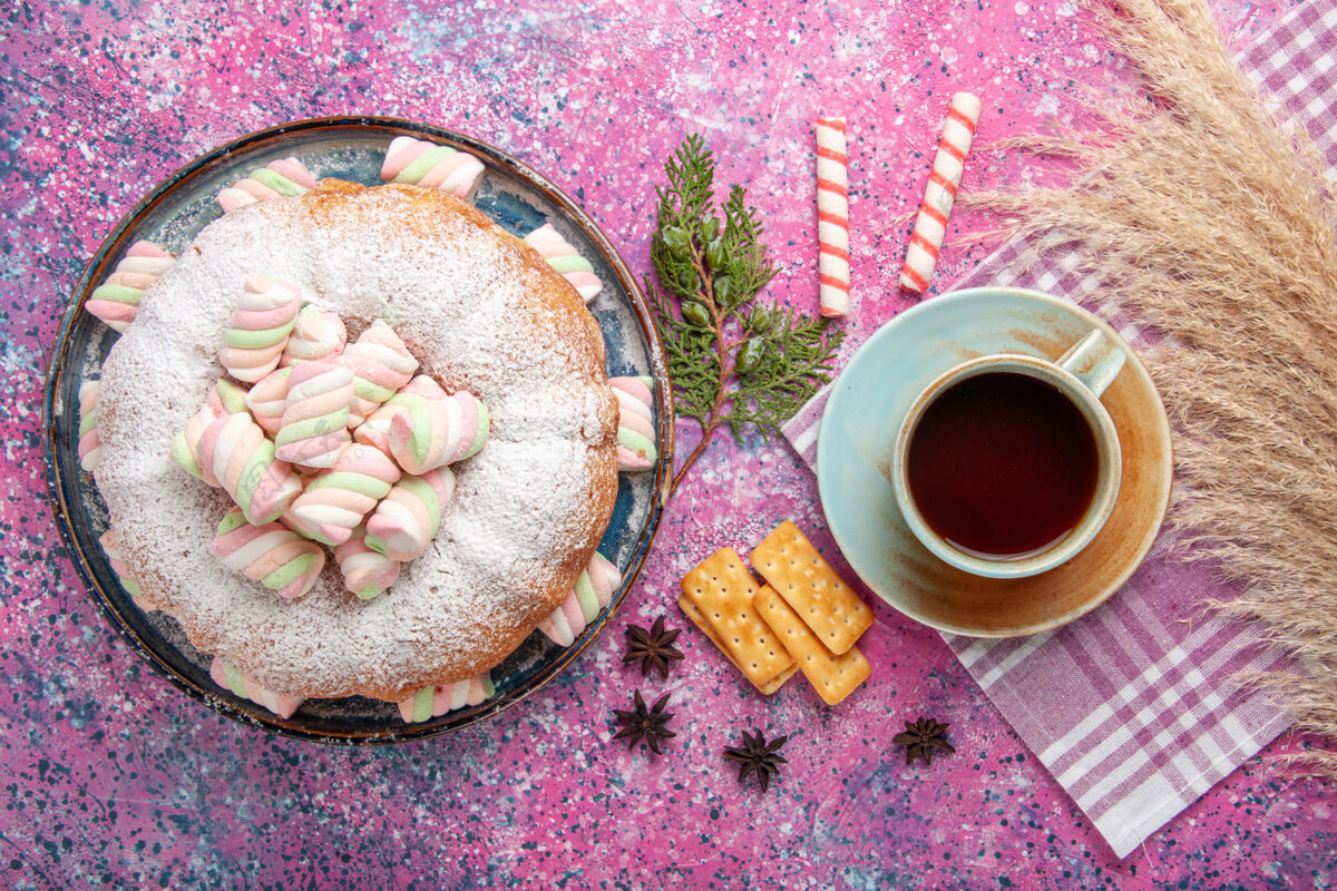美味在浅粉色表面上放一杯茶的糖粉蛋糕俯视图灯光食物美味