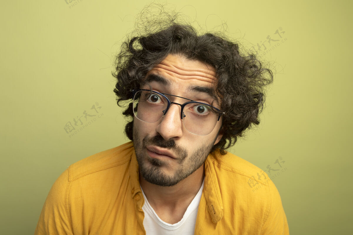 年轻特写镜头印象深刻的年轻帅哥戴着眼镜看着前面孤立的橄榄绿墙上立场表情印象