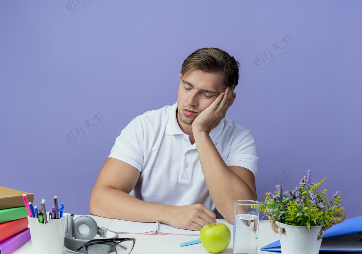 工具年轻英俊的男学生闭着眼睛坐在书桌旁 手里拿着学习用具 表现出睡觉的姿势 孤零零地躺在蓝色的椅子上男性蓝色手势